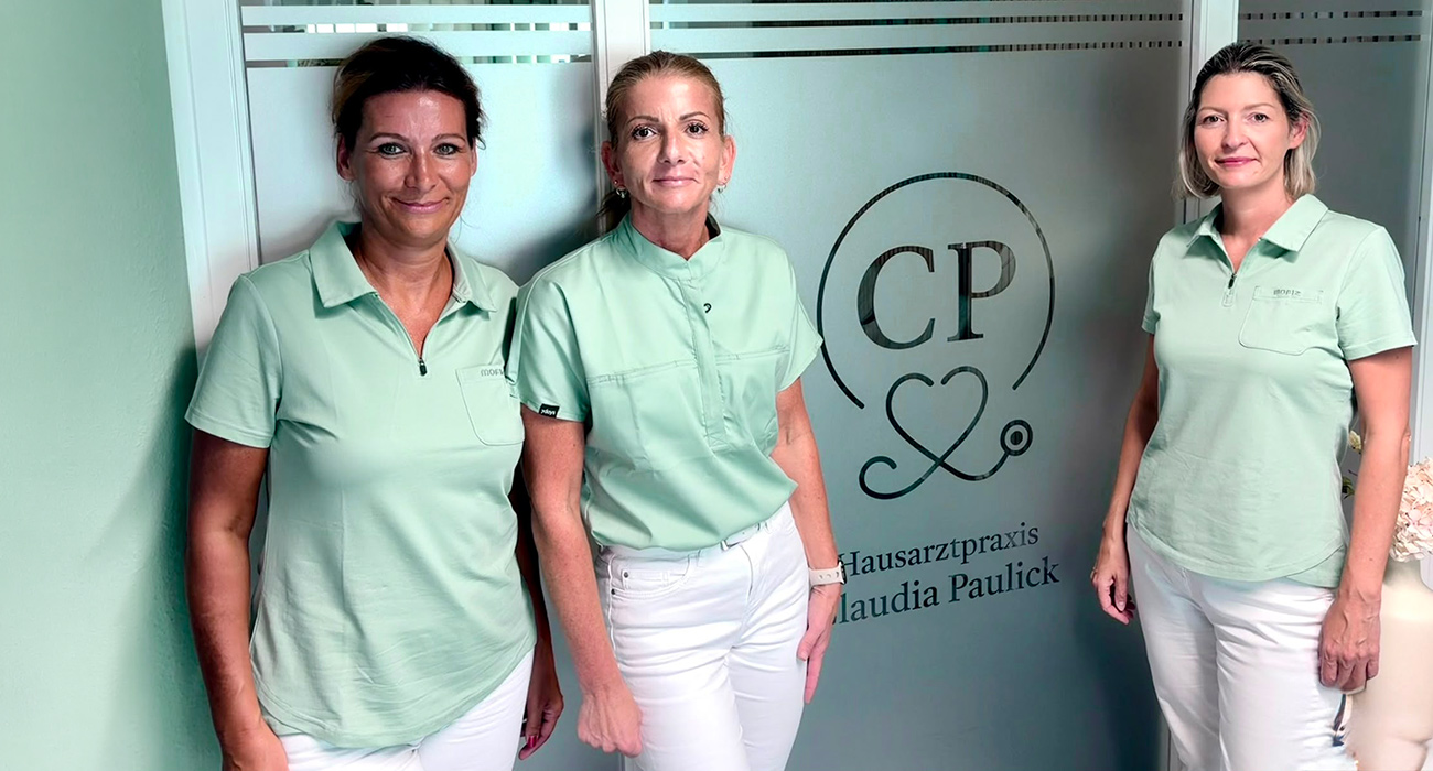 Claudia Paulick mit Schwester Steffi und Schwester Nicole vor einer Glaswand mit Logo
