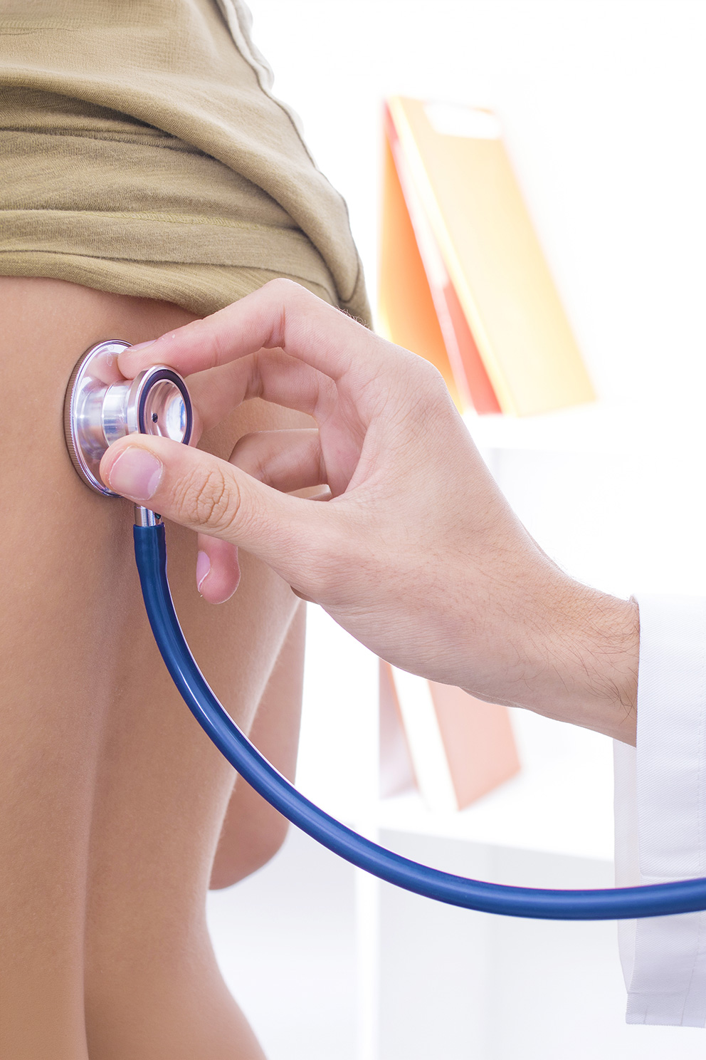 Hand am Stethoskop auf dem Rücken eines Patienten